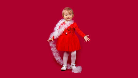 Hello December, awesome little girl welcome winter holidays. Christmas, sale and winter promotion concept on red background with plenty side spaceの写真素材