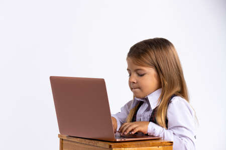 Online education for children. A schoolgirl teaches the school curriculum using a laptop. Photo on the white backgroundの写真素材
