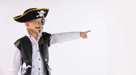 A boy from a kindergarten with a painted face saw something interesting in the distance and shows it with index finger. He is dressed for Halloween. Portrait on white background with empty side space. High quality photoの写真素材