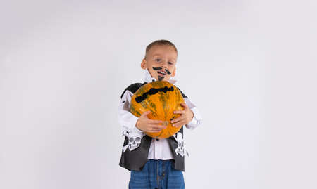 Adorable little boy, strong, having fun with a pumpkin on a beautiful autumn day. Kid collects yellow Halloween pumpkin. Autumn fun for children. High quality photoの写真素材