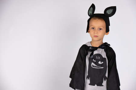 A humble boy in a bat costume. Carnival costume. Holiday concept. White isolated background with side blank space. High quality photoの写真素材