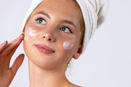 A sweet girl applied the cream to her cheeks, making the skin softer and more hydrated. Skin care...