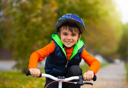 Portrait of a boy in the park. Small child wearing a helmet and cycling on an autumn day. Active healthy outdoor sportsの写真素材