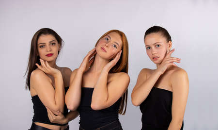 Three cute and attractive girls posing on a gray background in the studio. Spa and body beauty concept. Body and careの写真素材