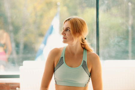 Beautiful young woman in the gym, resting after exercise. Profile photo.