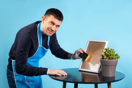 A man wipes the mirror and looks at the camera.Blue background.Gender stereotypeの写真素材