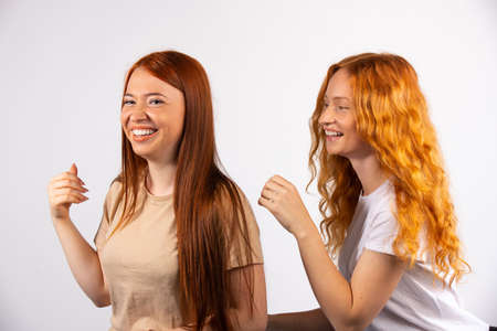 Two red-haired girlfriends are having fun. Photo on a white background. High quality photoの写真素材