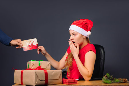Surprised girl elf receives a postcard while sitting at a table with gifts. High quality photo