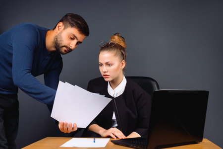 Business woman checks the plan of a young colleague in the office on a gray background. High quality photoの写真素材