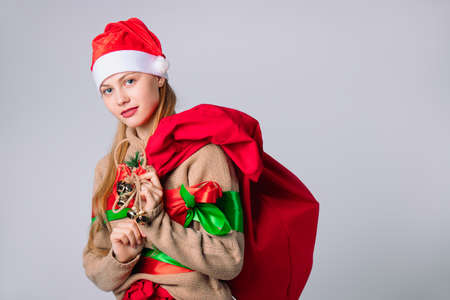 Santa Claus girl in New Year's outfit with and a big red bag of gifts on a white background. Wish and holidays concept. High quality photoの写真素材