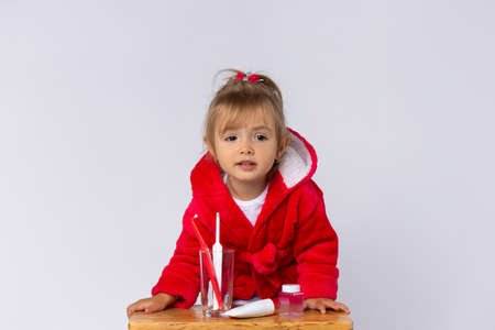Portrait of a little girl with a set of toothpaste and bills on a white background with blank space. High quality photoの写真素材