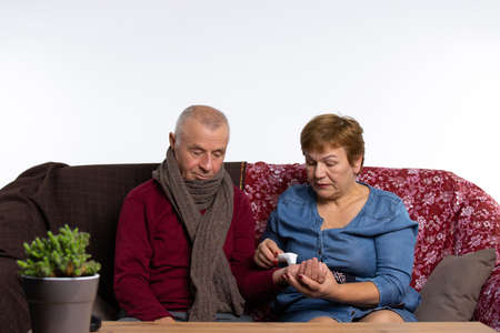 The elder woman takes care of her sick husband. An elderly couple is fighting a viral infection at home. High quality photoの写真素材