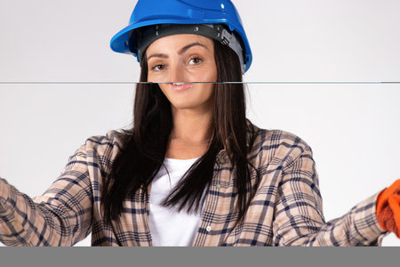 Portrait of young handywoman in a hard hat isolated on white. Gender stereotypes. High quality photoの写真素材