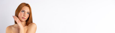 Banner. Red-haired girl with tender skin on a white background with empty side space. Glowing skin and skinimalism. High quality photoの写真素材