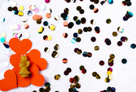 Textile background, candle in the shape of an angel, candy and red hearts. Concept for...