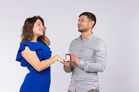 A happy girl receives engagement ring from her beloved man as marriage proposal. White background. Valentines day. High quality photoの写真素材