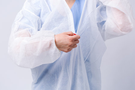 The doctor removes the protective gown after the work shift. Pandemic and coronavirus concept on white background. High quality photoの写真素材