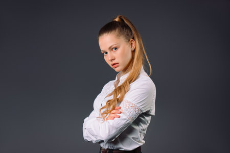 Portrait of a business woman who strictly looks at the camera and poses. Gray background and a lot of empty space.の写真素材