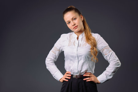 A cute business woman in a white shirt looks tenderly into the camera on a gray background with side space. Young entrepreneurs concept.の写真素材