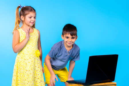 Children communicate via video link, the boy sat down in front of a laptop so that he could be seen better. Blue background.の写真素材