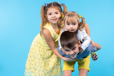 A group of children of different ages are playing and fooling around on a blue background with an...