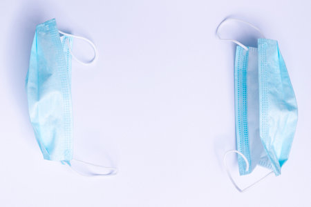 Two disposable medical masks on a white background with a blank space in the center.の写真素材