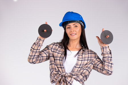 A brunette in a blue helmet looks at the camera, smiles and holds an imaging disk in her hands.の写真素材