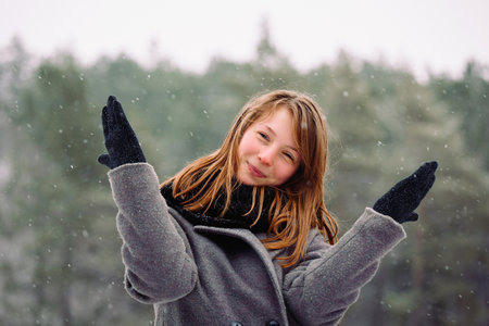 Portrait of a smiling girl who poses and has fun in the winter forest.の写真素材