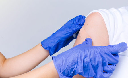Cropped photo. The hands of a healthcare professional in disposable gloves sticks a patch on the...