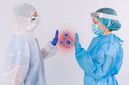 Two doctors in medical protective gear with latex gloves and an enlarged picture of germs in...