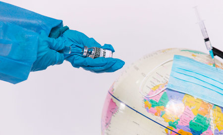 An enlarged photo in which the doctors hands hold an ampoule with a coronavirus vaccine and a...