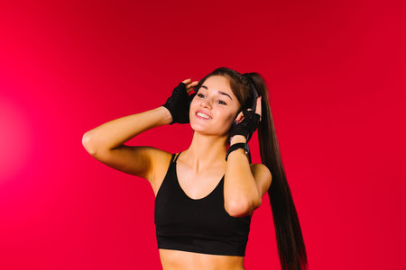 Portrait of a dancing girl wearing big headphones, looking to the side and smiling against a red background with empty side advertising space.の写真素材