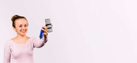 Banner, long format. A young smiling girl blogger communicates online with subscribers. Smiling and looking at the camera. White background. Side space.の写真素材