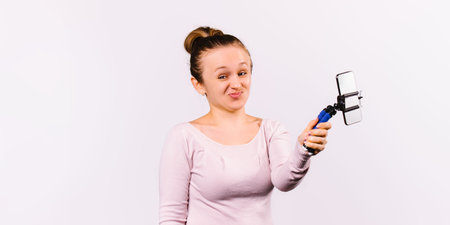 Banner. A young girl made a face and holds a smartphone and a selfie stick in her hand. Motivational...