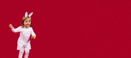 Banner,long format. Little happy girl with ears. Easter bunny. Smiling and cheering on a red...