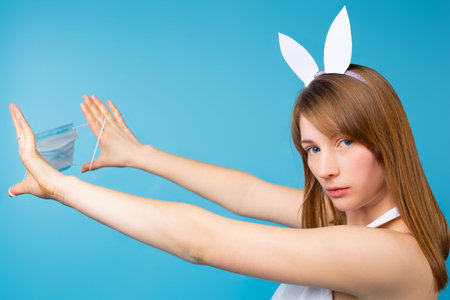 Portrait of a woman with easter bunny ears with a serious look looks into the camera and stretches a...
