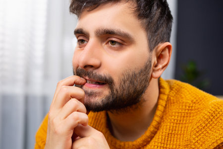 Close-up portrait of unhappy man, sad and thoughtful young businessman who thinks deeply, disturbed by mistakes, finger to mouth, looking in distance, a headache. Negative emotion. High quality photoの写真素材