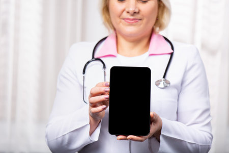 Cropped shot of a female doctor using a digital tablet, showing mock up empty screen to the camera....