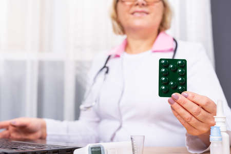 Cropped photo of senior female doctor talking with patient to inform about medication instructions. Elderly woman checking medical online information on laptop. High quality photoの写真素材