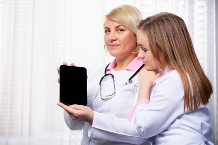 Modern medicine. Doctor showing test results on black mock up digital tablet screen. Two doctors using tablet in meeting at the medical office. High quality photoの写真素材