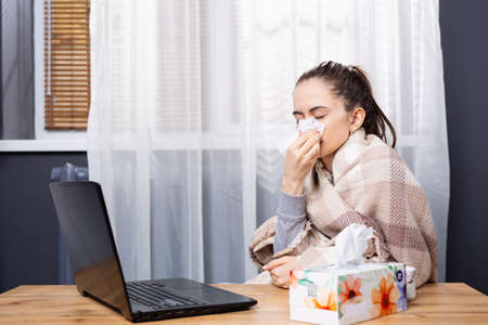 Caucasian ill brunette, young woman stay home and call medical doctor via telemedicine service to ask for medical advise using laptop. High quality photoの写真素材