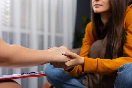 Care, trust, professionalism concept. Close up of therapist holding female patient hands, comforting her client. Support for addicted youth. High quality photoの写真素材