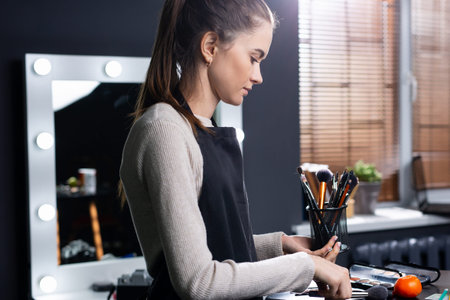 Professional make-up artist with makeup brushes at beauty workplace. Artist select decorative...