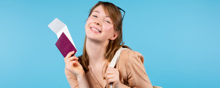 Banner,long format. Happy girl with a smile looks into the camera showing passport and ticket. Side advertising space. High quality photoの写真素材