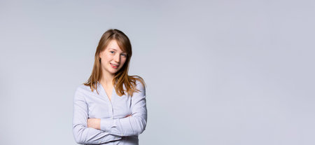 Young and attractive girl, dressed in casual clothes, isolated on a gray background, with her arms...