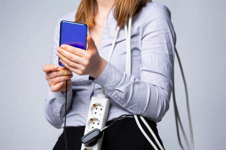 Cropped photo, young user of smartphone. Digital mobile technologies for communication concept. Female holding smartphone, woman carry cellphone charger wire or cable. High quality photoの写真素材
