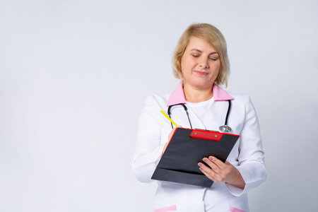 Female senior doctor, blonde caucasian with stethoscope are analyzing the data on the clipboard....