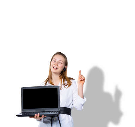 A contented blonde holds a laptop computer and points her finger up at an empty space where your text or advertisement could be. Idea on a white background with a gray shadow.の写真素材