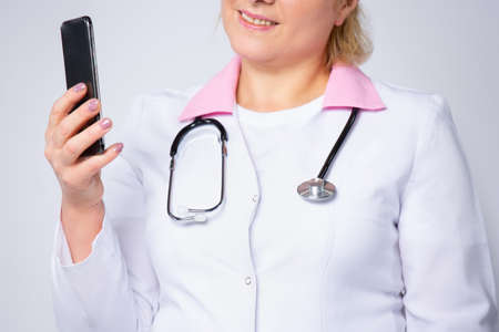 Cropped photo of female physician. Medicine, technology and healthcare concept - female doctor or nurse, healthworker calling on phone at hospital.の写真素材