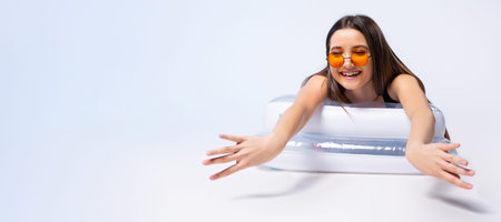 Banner,long format. A cheerful girl during a summer vacation lies on an inflatable mattress in...